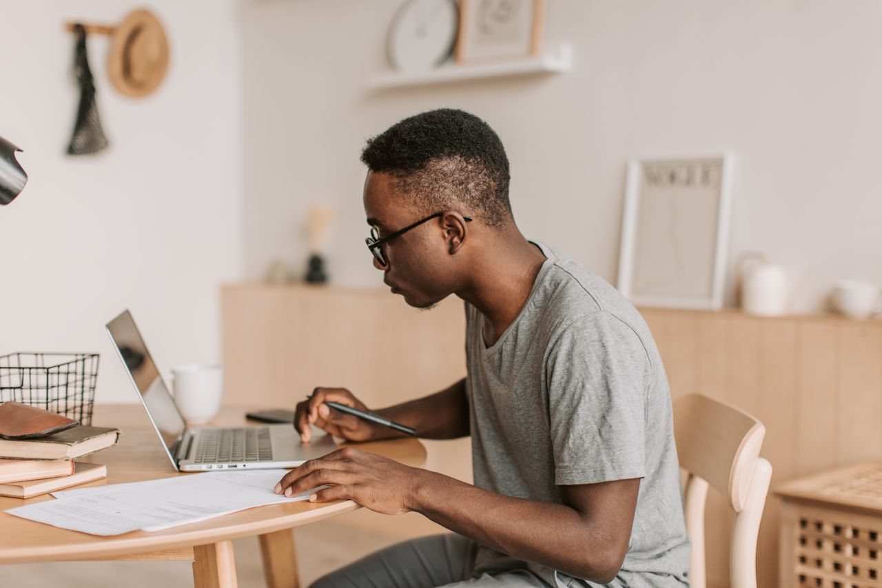 Nigerian university student working online with a laptop and smartphone while earning money through freelancing and digital opportunities