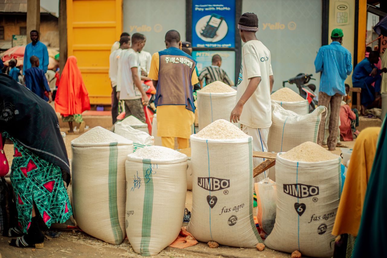 Foodstuff business owner arranging bags of rice, beans, garri and palm oil in a Nigerian grocery shop.